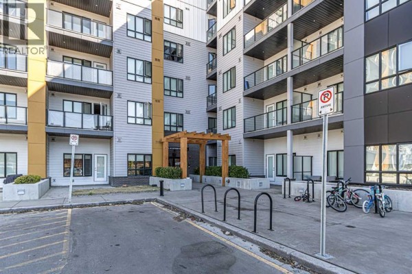 Exterior entrance to apartment building with wooden pergola and bicycle racks. - 3122, 60 Skyview Ranch Road Ne, Calgary