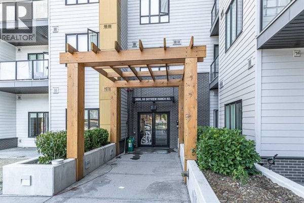 Close-up of building entrance with wooden pergola and apartment building number. - 3122, 60 Skyview Ranch Road Ne, Calgary