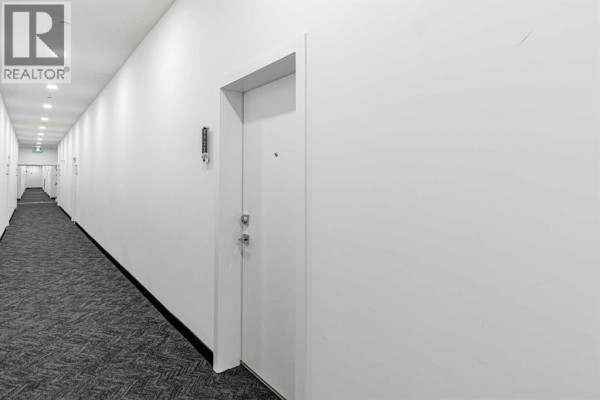 Interior hallway of apartment building with white walls and gray carpeted floor. - 3122, 60 Skyview Ranch Road Ne, Calgary