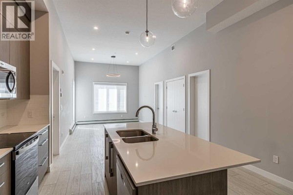Open concept living area with kitchen island, double sink, and large window. - 3122, 60 Skyview Ranch Road Ne, Calgary