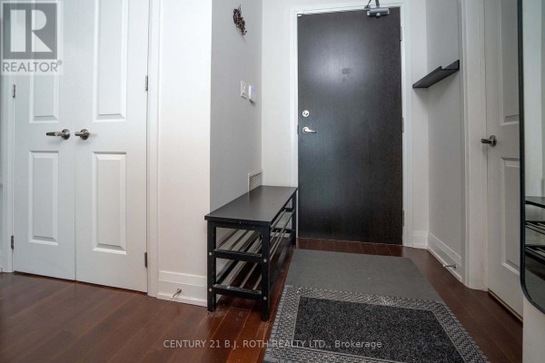 Entryway with bench, mirror, and hardwood flooring leading to the front door - 313 - 15277 Yonge Street S, Aurora