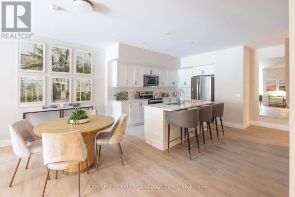 Open concept living and dining area with a kitchen island and dining table. - 313 - 230 North Centre Road, London North