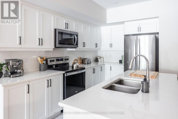 Kitchen island with a double sink and stainless steel refrigerator. - 313 - 230 North Centre Road, London North