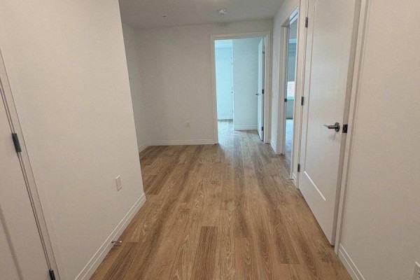 Interior hallway with light wood laminate flooring and white walls. - 313 - 351 Hill Street, London East