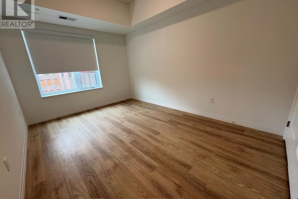 Empty room with light wood laminate flooring, white walls, and a window with blinds. - 313 - 351 Hill Street, London East