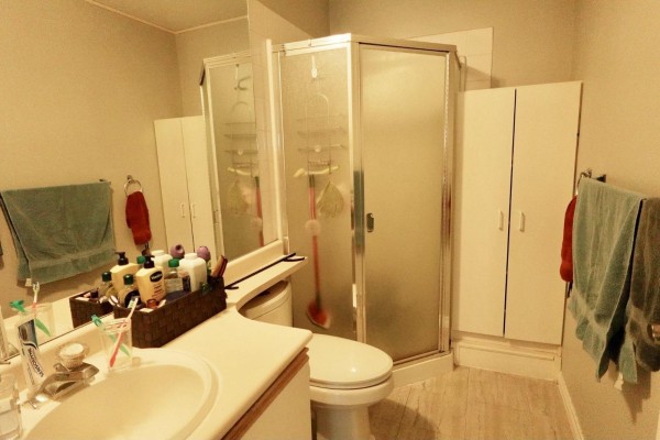 Bathroom with a sink, toilet, corner glass shower, and white cabinets. - 313 10756 138 Street, Surrey