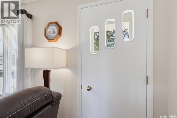 Interior front door with three small rectangular frosted glass panels and a wooden octagonal wall decoration. - 313 4th Avenue, Cudworth