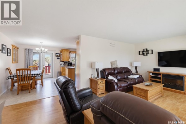 Living room with dark brown leather furniture and a coffee table, open to a dining area and kitchen. - 313 4th Avenue, Cudworth