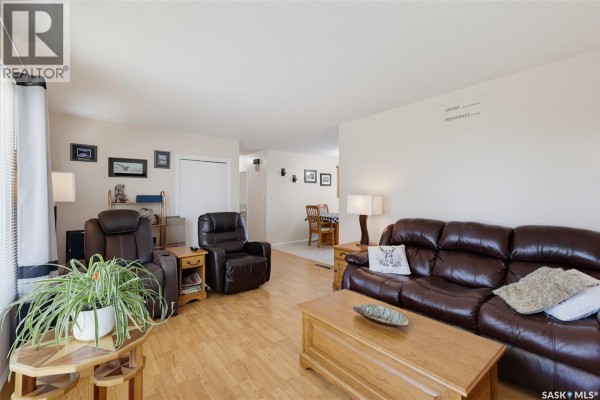 Living room with light wood flooring, brown leather sofas, a wooden coffee table, and a television with fireplace below. - 313 4th Avenue, Cudworth