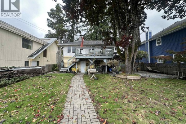 Backyard view featuring a stone pathway, deck, and surrounding greenery. - 313 E 13th Street, North Vancouver