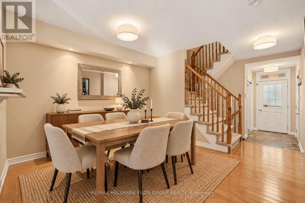 Dining room with wooden table, six chairs, buffet, mirror, and staircase leading upstairs. - 3130 Burritts Rapids Place, Ottawa