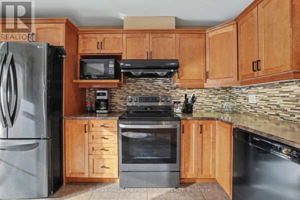 Close-up view of kitchen counters, gas range, microwave, coffee maker, and wooden cabinetry. - 3130 Burritts Rapids Place, Ottawa