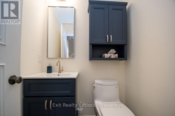 Dark blue vanity, toilet, and mirror in a modern bathroom - 3133 Frances Stewart Road Peterborough