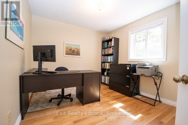 Office with dark wood desk, computer, bookshelf, and printer - 3133 Frances Stewart Road Peterborough