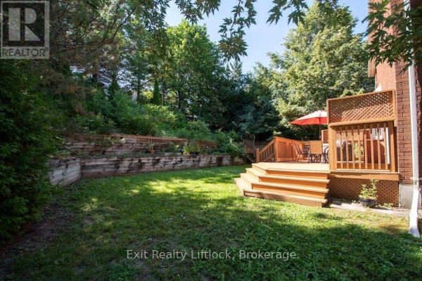 Wooden deck with dining set and red umbrella in backyard - 3133 Frances Stewart Road Peterborough