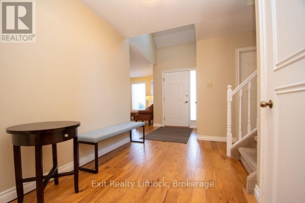 Foyer with wood flooring, a bench, a round table, and stairs to the right. - 3133 Frances Stewart Road, Peterborough
