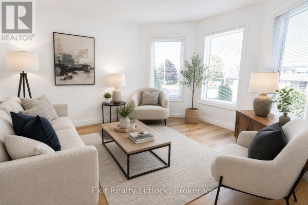 Living room with a sofa, armchairs, coffee table, and large bay windows. - 3133 Frances Stewart Road, Peterborough
