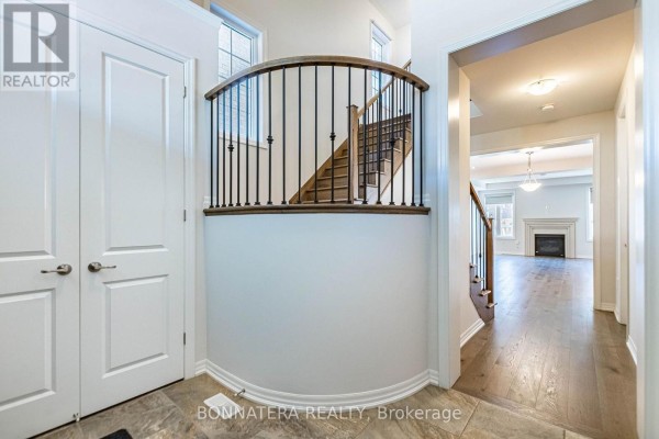 Foyer with view of curved staircase, hardwood floors, and living room. - 3136 Ernest Appelbe Boulevard, Oakville