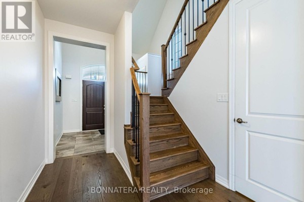 Hallway with view of curved staircase, dark hardwood floors, and closed doors. - 3136 Ernest Appelbe Boulevard, Oakville