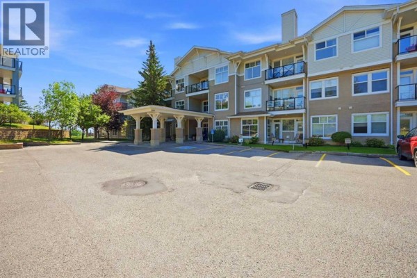 View of apartment building from parking lot with grassy areas. - 3137, 1010 Arbour Lake Road Nw, Calgary