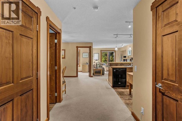 View from the apartment entrance showing a hallway with wood doors leading to a living area. - 314, 170 Crossbow Place, Canmore