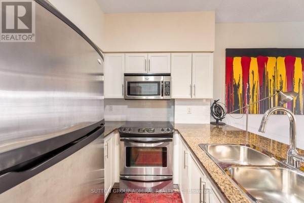 Close-up of a kitchen with stainless steel appliances, granite countertop, and double sink. - 314 - 15 Windermere Avenue, Toronto