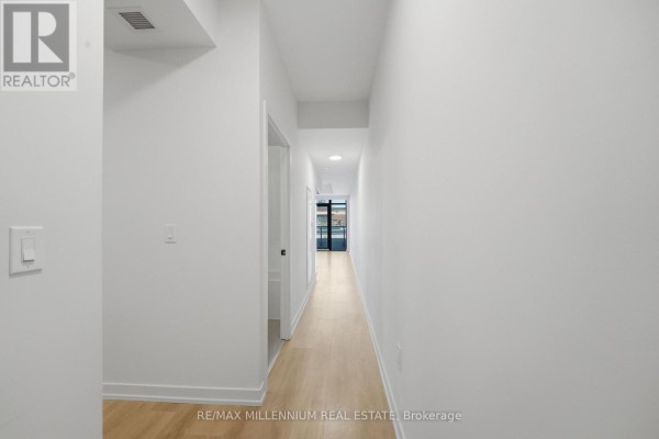 Open concept living area with a modern kitchen, stainless steel appliances, and large balcony doors. - 314 - 181 Sterling Road, Toronto