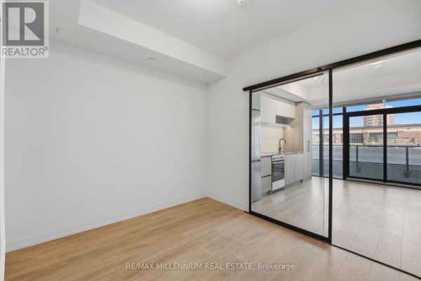 Kitchen area with light wood cabinets, white tiled backsplash, stainless steel fridge, and oven. - 314 - 181 Sterling Road, Toronto