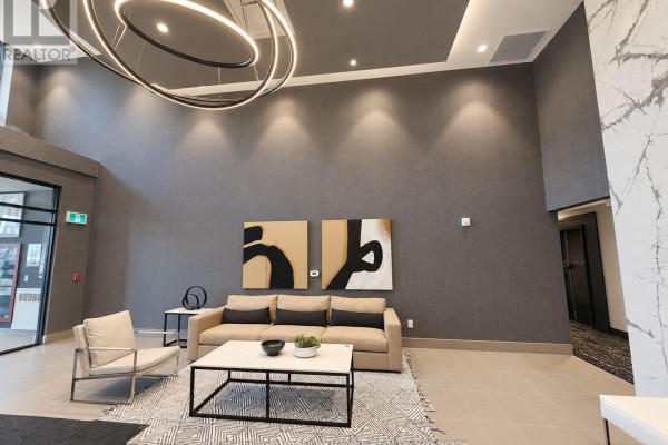 Lobby with a tan sofa, modern chairs, coffee table, and marble fireplace. - 314 - 470 Gordon Krantz Avenue, Milton