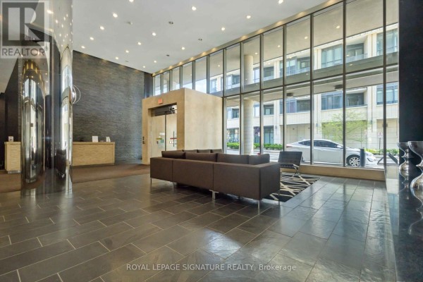 Building lobby with dark tiled floor, modern seating, and large glass windows. - 314 - 55 East Liberty Street, Toronto