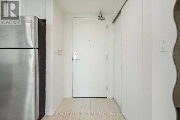 Apartment entrance door with stainless steel refrigerator to the left. - 314 - 55 East Liberty Street, Toronto
