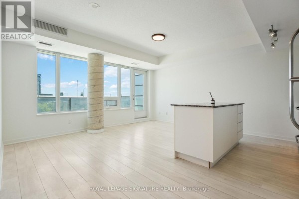 Empty open concept living area and kitchen with island and large windows. - 314 - 55 East Liberty Street, Toronto