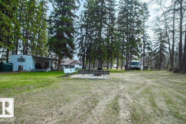 Grassy yard with picnic tables and RVs parked in a wooded area. - #314 & 315 55230 Rge Rd 10, Rural Sturgeon County