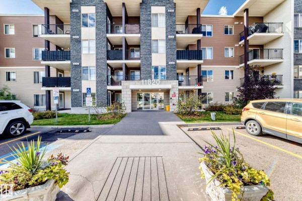Entrance to a modern apartment building with a covered walkway and potted plants. - #314 11820 22 Av Sw, Edmonton