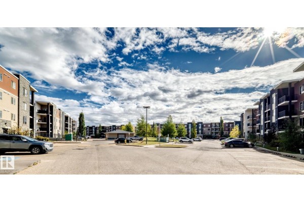 Wide exterior view of apartment buildings surrounding a large parking lot. - #314 11820 22 Av Sw, Edmonton
