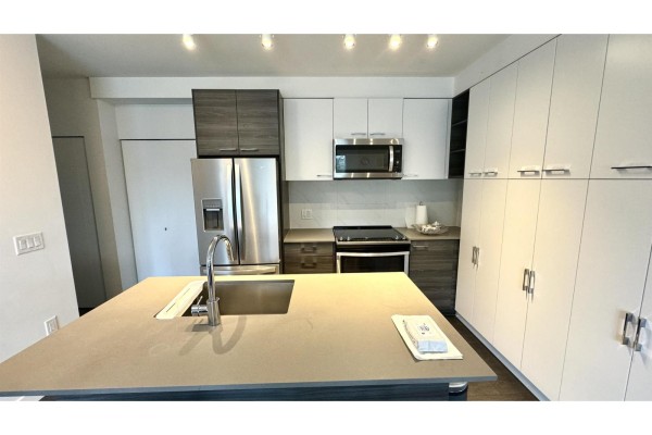 Modern kitchen with stainless steel appliances, island, and ample cabinetry. - 314 13963 105a Boulevard, Surrey