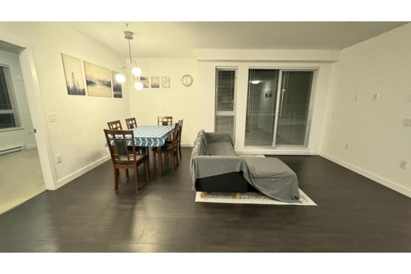 Apartment living and dining area with couch, dining set, and patio doors. - 314 13963 105a Boulevard, Surrey