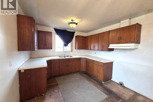 U-shaped kitchen with dark wood cabinets, white laminate countertops, and a double sink. - 314 2nd Avenue, Young