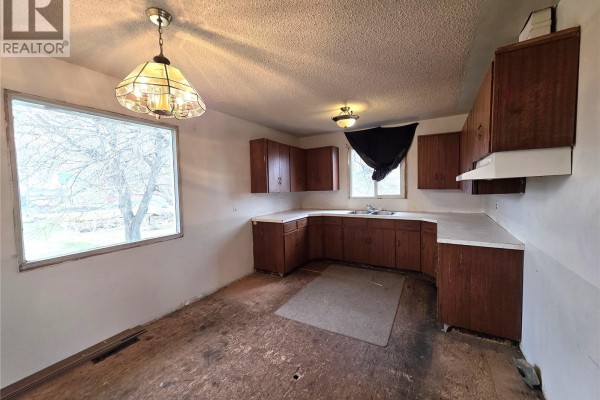 Kitchen with dark wood cabinets, white countertops, and a large window looking out onto trees. - 314 2nd Avenue, Young