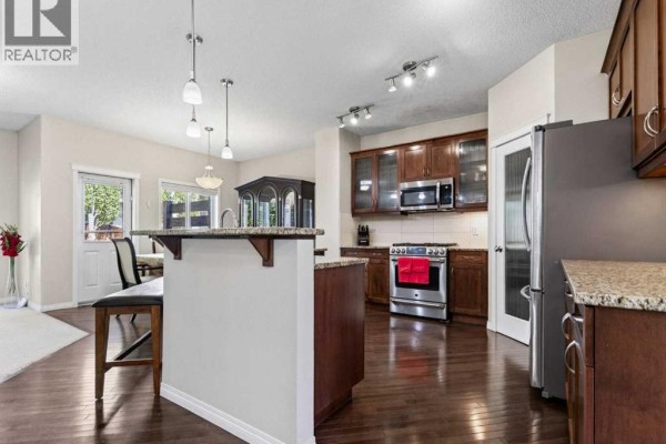 Bedroom with large wooden bed frame, white bedding, and two teal accent chairs. - 314 Reunion Heath Nw, Airdrie