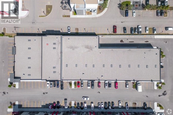 Top-down view of a long commercial building with a grey roof and surrounding parking lot. - 3140, 6520 36 Street Ne, Calgary