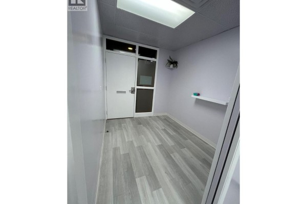 Entrance area with white door, small window, and grey wood-look flooring. - 3140 Lakeshore Road Unit# 203, Kelowna