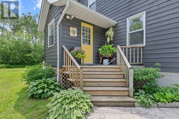 Close-up of the yellow front door and wooden steps leading to the covered porch of a dark grey house. - 3147 Dalton Court, Tay
