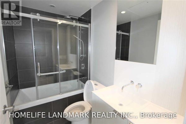 Close-up of a bathroom with dark tile shower, toilet, and modern vanity. - 315 - 1990 Bloor Street W, Toronto