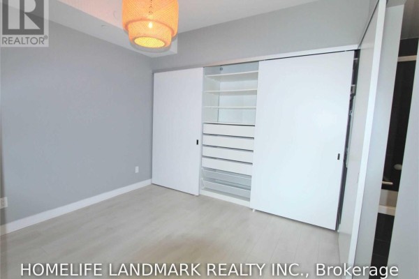 Bedroom with light wood floor, grey walls, and a large built-in white closet. - 315 - 1990 Bloor Street W, Toronto