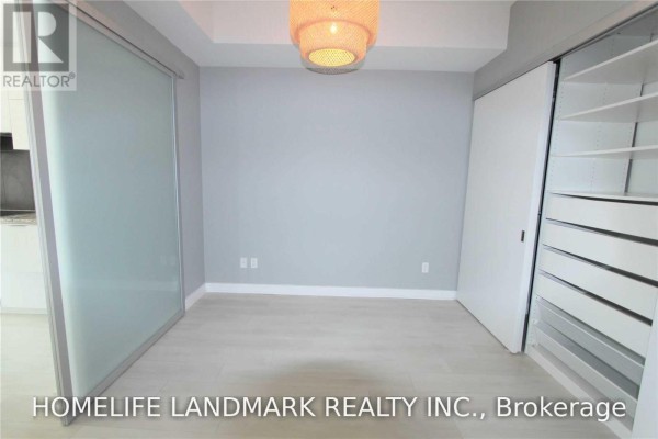 Bedroom with sliding frosted glass door on left, grey walls, and built-in closet. - 315 - 1990 Bloor Street W, Toronto
