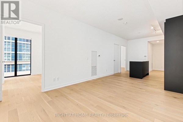 Empty living room with light wood floors and doors leading to a bathroom and balcony. - 315 - 25 Richmond Street E, Toronto
