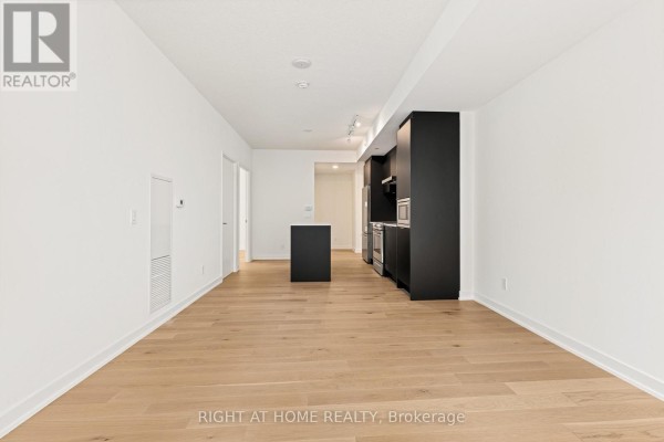 View of the modern kitchen with black cabinetry and stainless steel appliances, and a dark island. - 315 - 25 Richmond Street E, Toronto
