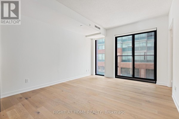 Bedroom with light wood floors and large windows offering a view of the surrounding cityscape. - 315 - 25 Richmond Street E, Toronto