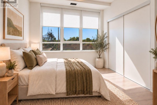 Bedroom with bed, bedside tables, plant, and mirrored closet doors. - 315 - 286 Main Street, Toronto